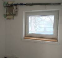 Místnost s oknem a potrubím na stěně ve výrobních prostorách.