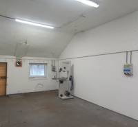 Výrobní prostory s bílými stěnami, nářadím a osvětlením, bez podlahy s dřevěným dekorem.