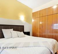 Ložnice s postelí a vestavěnou skříní, Rodinný dům. Neutrální barvy, podlaha s dřevěným dekorem.