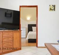 Interiér rodinného domu s velkou televizí, otevřené dveře do ložnice, dekorace.