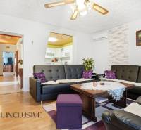 Obývací pokoj v rodinném domě s podlahou s dřevěným dekorem a černými koženými sedačkami.