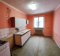 Kuchyně v 2-pokojovém bytě s oranžovými stěnami a jednoduchou kuchyňskou linkou.