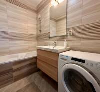 Koupelna s vanou, umyvadlem a pračkou v 3-pokojovém bytě.