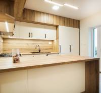 Kuchyně s podlahou s dřevěným dekorem, světlá atmosféra a výhled do zahrady.