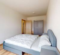 Ložnice ve 3-pokojovém bytě s postelí, šatní skříní a podlahou s dřevěným dekorem.