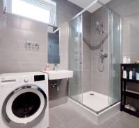 Koupelna v 3-pokojovém bytě s pračkou, sprchovým koutem a umyvadlem.