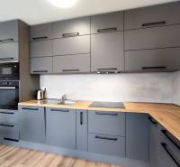 Stylová kuchyně v 3-pokojovém bytě s podlahou s dřevěným dekorem a šedými skříňkami.