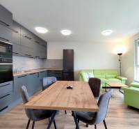 Světlá kuchyně s jídelním stolem a pohovkou ve 3-pokojovém bytě s podlahou s dřevěným dekorem.