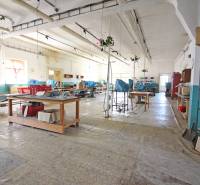 Interiér budovy s velkou halou, pracovními stoly a policemi.