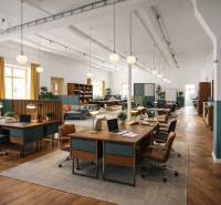 Interiér budovy s kancelářskými stoly, židlemi, podlahou s dřevěným dekorem a osvětlením.