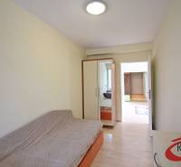 Pokoj v 3-pokojovém bytě s pohovkou, vestavěnou skříní a podlahou s dřevěným dekorem.