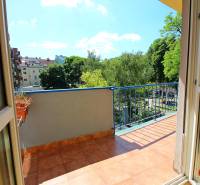 Balkon 3pokojového bytu s výhledem na zeleň a další budovy.