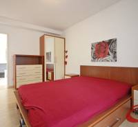 Ložnice s podlahou s dřevěným dekorem, postelí, skříňkou a obrazem v 3-pokojovém bytě.