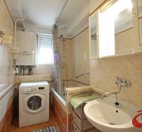 Koupelna s vanou a pračkou ve 3-pokojovém bytě, s obklady krémové barvy.