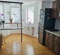 Kuchyně v rodinném domě s podlahou s dřevěným dekorem, tmavým nábytkem a barovým pultem.