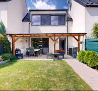 Zahrada a terasa u rodinného domu ve Stupavě s upraveným trávníkem a záhonem.