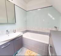 Koupelna s vanou v rodinném domě, elegantní doplňky a světlé barevné tóny.