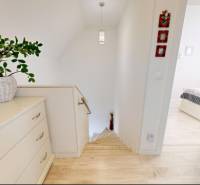 Interiér rodinného domu s podlahou s dřevěným dekorem a světlým nábytkem.