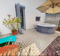 Na zahradě rodinného domu ve Stupavě jsou lehátka, vířivka a slunečník.