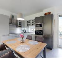 Kuchyně v rodinném domě s jídelním stolem a vstupem na terasu.