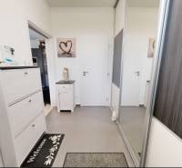 Interiér rodinného domu s bílým nábytkem a zrcadlovou skříní. Razítko a logo na obrázku.