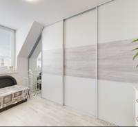 Interiér rodinného domu se světlou místností, pohovkou a rostlinou, podlaha s dřevěným dekorem.