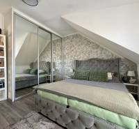 Interiér 2-pokojového bytu s podlahou s dřevěným dekorem, šikmým stropem a zrcadlovou skříní.