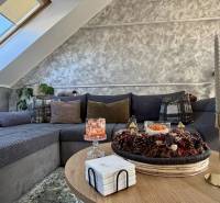 Obývací pokoj v 2-pokojovém bytě s dekorativními polštáři na pohovce a svíčkami na stole.