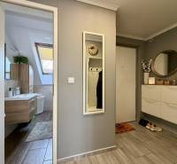 Předsíň s podlahou s dřevěným dekorem, zrcadlem a koupelnou v 2-pokojovém bytě.