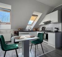 Kuchyně v 2-pokojovém bytě s podlahou s dřevěným dekorem a stolem se židlemi.