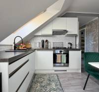 Kuchyně v 2-pokojovém bytě se šikmým stropem a podlahou s dřevěným dekorem.