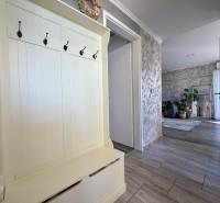 Vstupní chodba v 2pokojovém bytě s věšáky, vedoucí do obývacího pokoje s rostlinami.