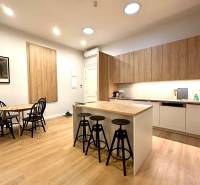 Kuchyně v 2-pokojovém bytě s ostrůvkem, židlemi a podlahou s dřevěným dekorem.
