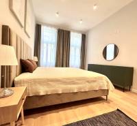 Ložnice v 2-pokojovém bytě s velkou postelí, lampou a podlahou s dřevěným dekorem.