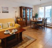 Obývací pokoj v rodinném domě s jídelním stolem, policemi a pohovkou.