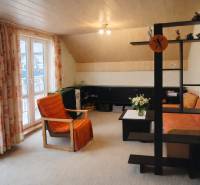 Obývací pokoj s oranžovým křeslem a pohovkou v rodinném domě.