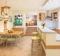 Kuchyně a jídelna s barem v rodinném domě, světlé odstíny a akvárium.