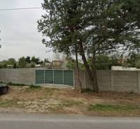 Pozemky - komerční na Dukelské v Bernolákově s betonovým plotem a příjezdovou cestou.