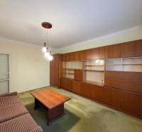 Obývací pokoj v 3-pokojovém bytě s dřevěnou stěnovou sestavou a gaučem.