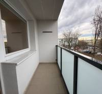 Balkon 3pokojového bytu v Komárně na Košické ulici s výhledem na parkoviště a stromy.