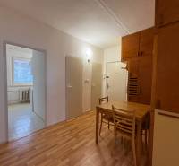 Interiér 3-pokojového bytu s podlahou s dřevěným dekorem, jídelní kout se stolem a židlemi.