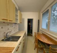 Kuchyně v 3-pokojovém bytě s dřevěným dekorem, dřevěný stůl a kachličkový obklad.