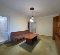 Obývací pokoj třípokojového bytu s pohovkou, konferenčním stolkem a vitrínou.