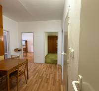 Interiér 3-pokojového bytu s podlahou s dřevěným dekorem, stolem a židlemi.