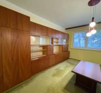 Obývací pokoj s dřevěným nábytkem a kobercem ve 3-pokojovém bytě.