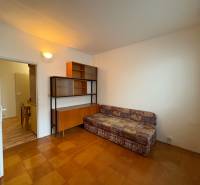 Pokoj v 3-pokojovém bytě s pohovkou, skříňkou a podlahou s dřevěným dekorem.