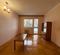 Obývací pokoj ve 3-pokojovém bytě s podlahou s dřevěným dekorem a jednoduchým nábytkem.