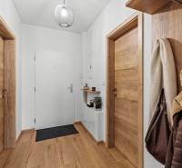 Chodba v 2-pokojovém bytě s podlahou s dřevěným dekorem a dřevěnými dveřmi.