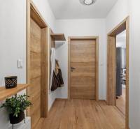 Chodba v 2-pokojovém bytě s dřevěnými dveřmi a podlahou s dřevěným dekorem.