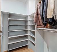 Šatník s policemi a věšáky v 2-pokojovém bytě s podlahou s dřevěným dekorem.